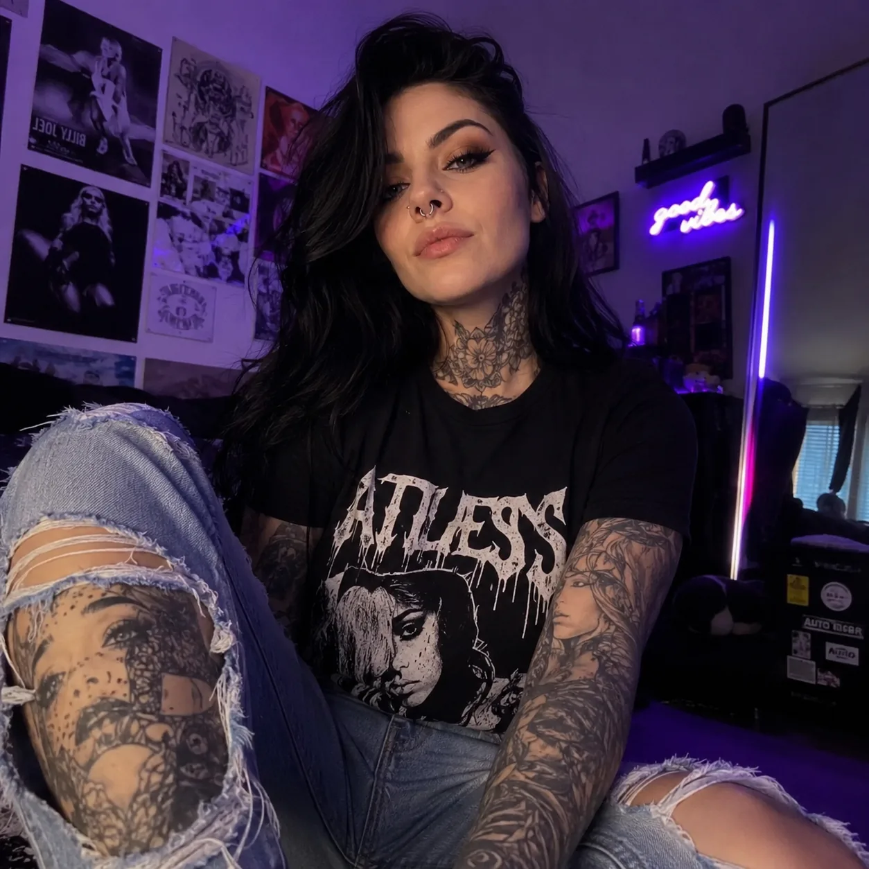 Tattooed content creator in a graphic t-shirt in a softly lit room